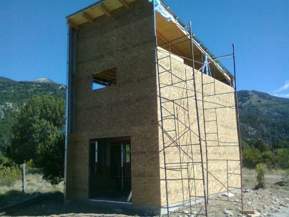 Casa en construcción en seco con placas OSB y andamios en valle de montaña